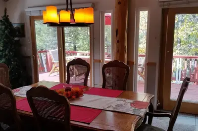 a dining room with a table and chairs and windows at Dream Getaway-Secluded Hot Spa-Walk to Village-Walk to Pineknot Trailhead-Plus King Bed! in Big Bear Lake