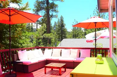 a couch on a deck with a table and umbrellas at Dream Getaway-Secluded Hot Spa-Walk to Village-Walk to Pineknot Trailhead-Plus King Bed! in Big Bear Lake