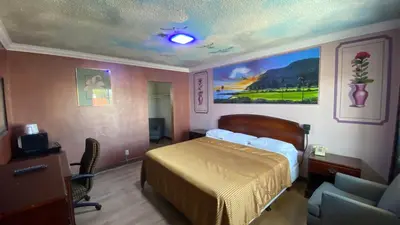 a bedroom with a bed and a desk and a chair at Villa Park Motel in Orange