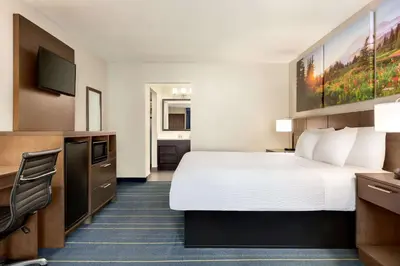 a hotel room with a bed and a flat screen tv at Days Inn & Suites by Wyndham Anaheim At Disneyland Park in Anaheim