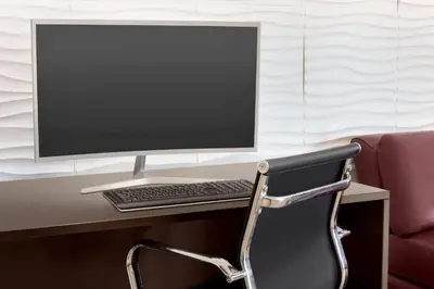 a computer monitor sitting on a desk with a chair at Days Inn & Suites by Wyndham Anaheim At Disneyland Park in Anaheim