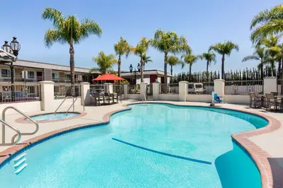 a large swimming pool with palm trees in the background at Days Inn & Suites by Wyndham Anaheim At Disneyland Park in Anaheim