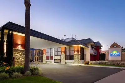 a hotel with a palm tree in front of a building at Days Inn & Suites by Wyndham Anaheim At Disneyland Park in Anaheim