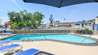 a swimming pool with chairs and an umbrella at Sea Rock Inn - Long Beach in Long Beach