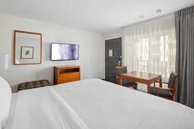 a bedroom with a large white bed and a table at Vagabond Inn Glendale in Glendale