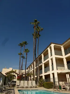 a resort with a pool and palm trees and a building at Vagabond Inn Glendale in Glendale