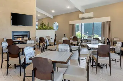 a restaurant with tables and chairs and a fireplace at Best Western Plus Executive Inn Rowland Height City of Industry in Rowland Heights