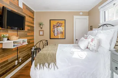a bedroom with a white bed and a flat screen tv at Casita Gundry- Boutique Hideaway, Quaint Historic Charm in Long Beach