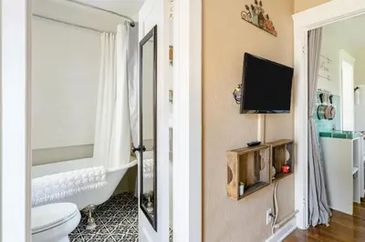 a bathroom with a toilet and a tv on a wall at Casita Gundry- Boutique Hideaway, Quaint Historic Charm in Long Beach