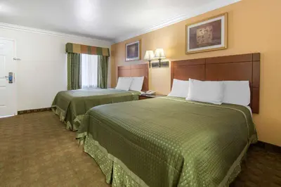 two beds in a hotel room with green sheets at Rodeway Inn Adelanto US 395 in Adelanto