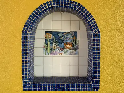 an arched window with blue tiles on a yellow wall at Sandyland Reef Inn in Carpinteria