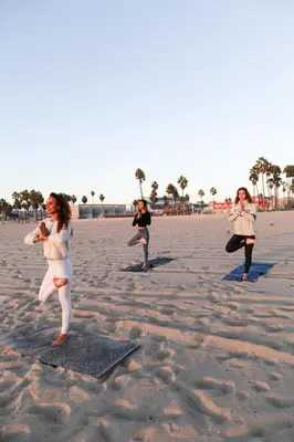 three women are doing yoga on the beach at Ocean Front Vortex Female Hostel private rooms Free bikes in Los Angeles
