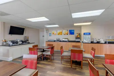 a dining room with tables and chairs and a kitchen at Comfort Suites Victorville-Hesperia in Victorville