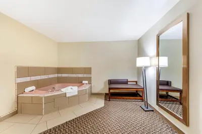 a bathroom with a tub and a chair and a mirror at Comfort Inn & Suites Lancaster Antelope Valley in Lancaster