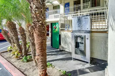 a parking meter next to a building with a palm tree at Motel 6 Garden Grove in Anaheim