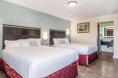 two beds in a hotel room with white sheets at Rodeway Inn Barstow Route 66 in Barstow