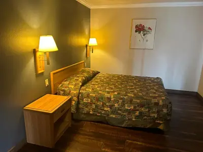 a hotel room with a bed and a table at Palm Inn Hotel near Tyler Mall Riverside in Riverside