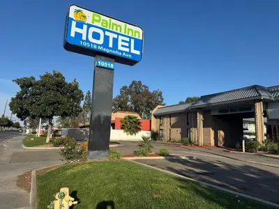 a sign for a hotel in front of a building at Palm Inn Hotel near Tyler Mall Riverside in Riverside