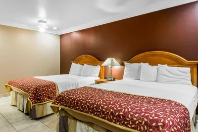 a hotel room with two beds and a lamp at Rodeway Inn Cypress - Buena Park in Cypress