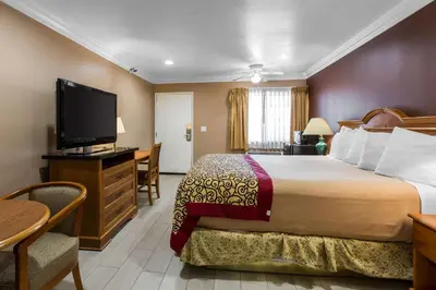 a hotel room with a bed and a flat screen tv at Rodeway Inn Cypress - Buena Park in Cypress