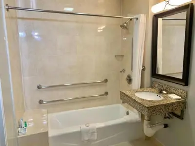 a bathroom with a tub and a sink and a mirror at Tilt Hotel Universal-Hollywood, an AGA Collection Hotel in Los Angeles