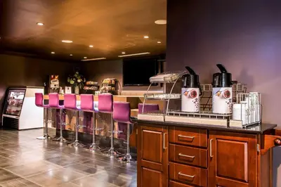 a bar with pink bar stools and a counter with at Tilt Hotel Universal-Hollywood, an AGA Collection Hotel in Los Angeles