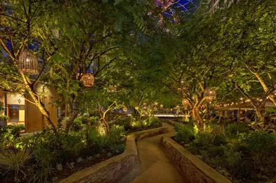 a garden with trees and a walkway at night at 1 Hotel West Hollywood in Los Angeles
