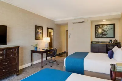 a hotel room with two beds and a desk at Ayres Suites Diamond Bar in Diamond Bar