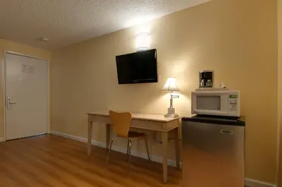 a room with a desk with a microwave and a refrigerator at Vagabond Inn Bakersfield South in Bakersfield