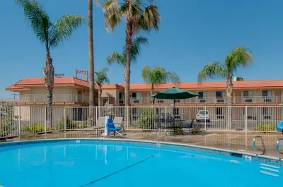 a swimming pool in front of a hotel with palm trees at Vagabond Inn Bakersfield North in Bakersfield
