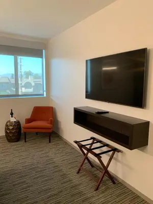 a living room with a flat screen tv and a chair at Hotel Mariposa in Los Angeles