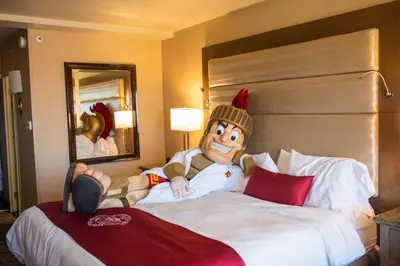 a large doll sitting on a bed in a hotel room at USC Hotel in Los Angeles