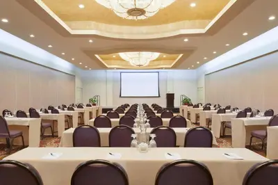 a conference room with tables and chairs and a projection screen at USC Hotel in Los Angeles