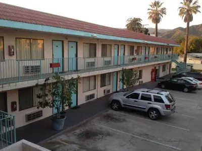 a car parked in a parking lot in front of a motel at All 8 Motel in Azusa