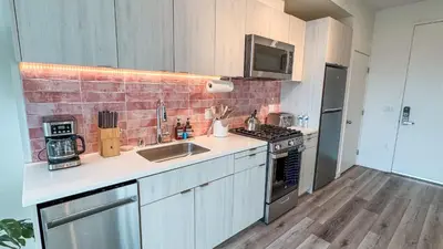 a kitchen with white cabinets and a brick wall at Lovely Studio in heart of Hollywood in Los Angeles