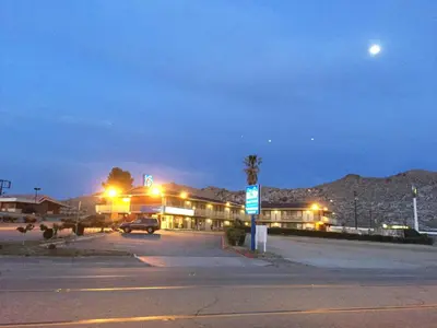 an empty parking lot in front of a hotel at night at Hilltop Inn & Suites in Victorville