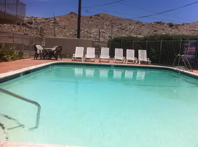 a large swimming pool with chairs and a table at Hilltop Inn & Suites in Victorville