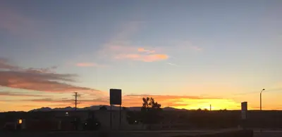 a sunset over a city with mountains in the background at Hilltop Inn & Suites in Victorville