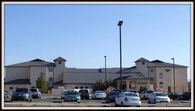 a parking lot with cars parked in front of a building at Landmark Inn Fort Irwin in Fort Irwin