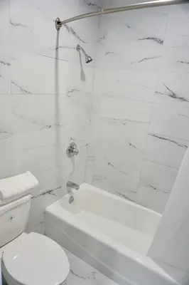 a white bathroom with a toilet and a bath tub at Redondo Beach Motel - LAX in Gardena