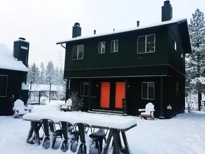a black house with snow covered tables in front of it at Noon Lodge in Big Bear Lake