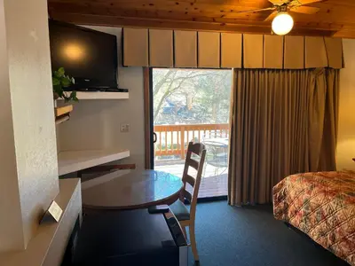 a hotel room with a table and a bed and a balcony at Whispering Pines Lodge in Kernville