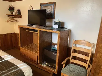 a bedroom with a tv and a bed and a chair at Whispering Pines Lodge in Kernville