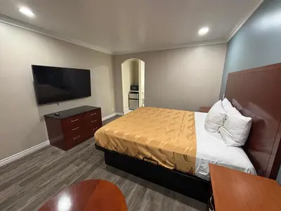 a hotel room with a bed and a flat screen tv at Economy Inn - Burbank Airport in Sun Valley