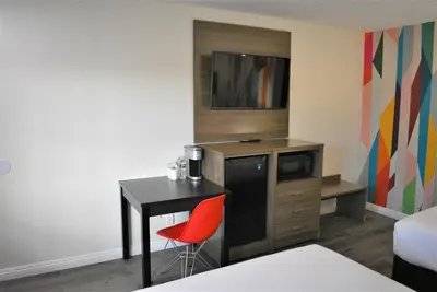 a room with a desk and a tv and a table with a chair at Signature Anaheim Maingate in Anaheim