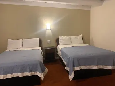 a bedroom with two beds and a light on the wall at Ventura Beach House Motel in Ventura