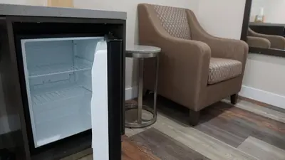 an open refrigerator next to a chair and a table at Sea Breeze Inn - LAX Airport, Los Angeles in Inglewood