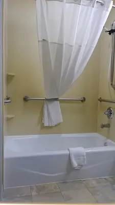 a bathroom with a bath tub with a shower curtain at Microtel Inn & Suites by Wyndham Wheeler Ridge in Wheeler Ridge