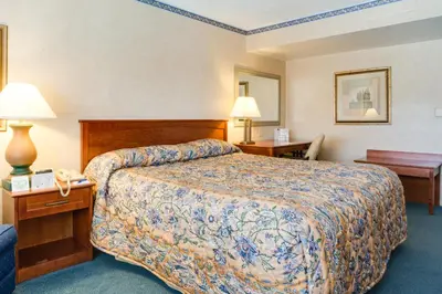 a hotel room with a bed and two tables and lamps at Saga Motor Hotel Pasadena in Pasadena