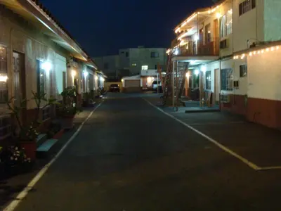 an empty street at night with lit up buildings at American Inn in South El Monte